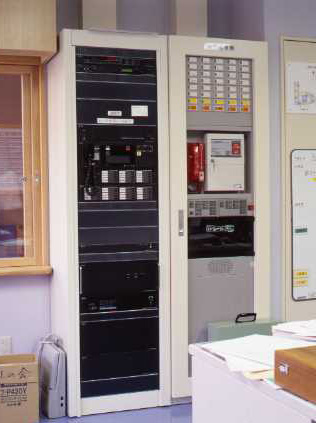 受付を兼ねた事務室に設置された非常・業務用放送設備ラック